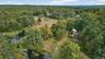 Aerial view of property and surrounding area with a large body of water and a heavily wooded area