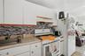 Kitchen with white range with gas cooktop, light countertops, white cabinets, and tasteful backsplash