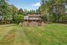 Rear view of property with a deck, a lawn, and brick siding