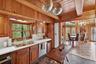 Kitchen with brown cabinetry, light countertops, a chandelier, dishwasher, and a wooden ceiling with exposed beams