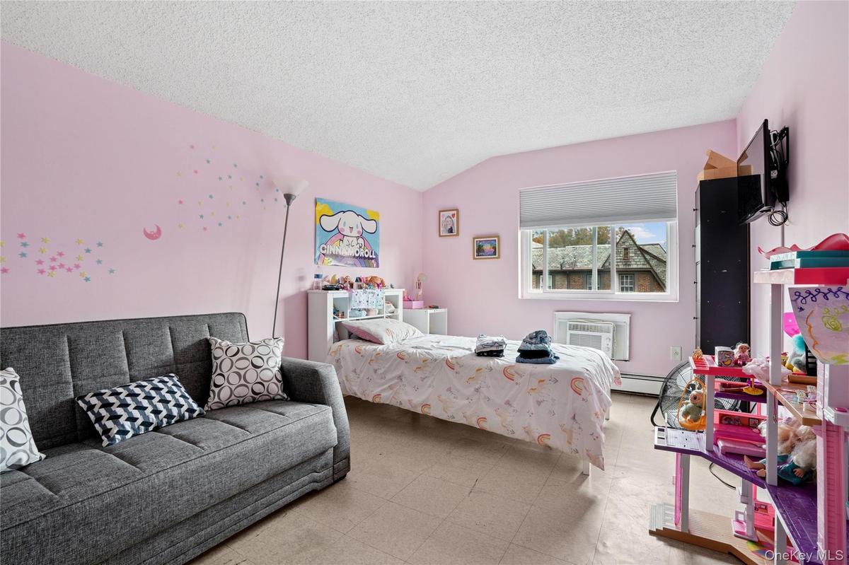 Bedroom featuring tile patterned floors, a textured ceiling, lofted ceiling, a wall unit AC, and a baseboard heating unit
