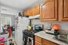 Kitchen with stainless steel range with gas cooktop, backsplash, under cabinet range hood, light tile patterned floors, and brown cabinets