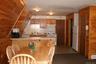 Kitchen featuring a peninsula, light countertops, white appliances, wooden walls, and under cabinet range hood