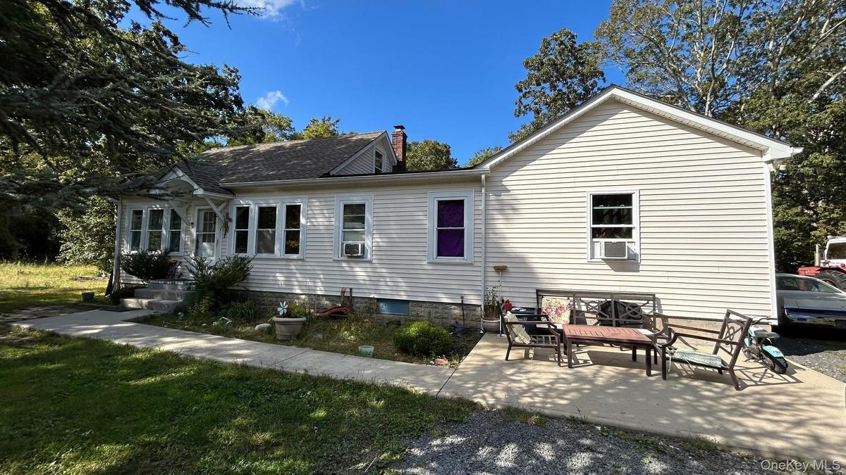 Rear view of property featuring a chimney, a patio area, and a yard