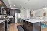 Kitchen featuring appliances with stainless steel finishes, light stone counters, light wood-style flooring, decorative backsplash, and an island with