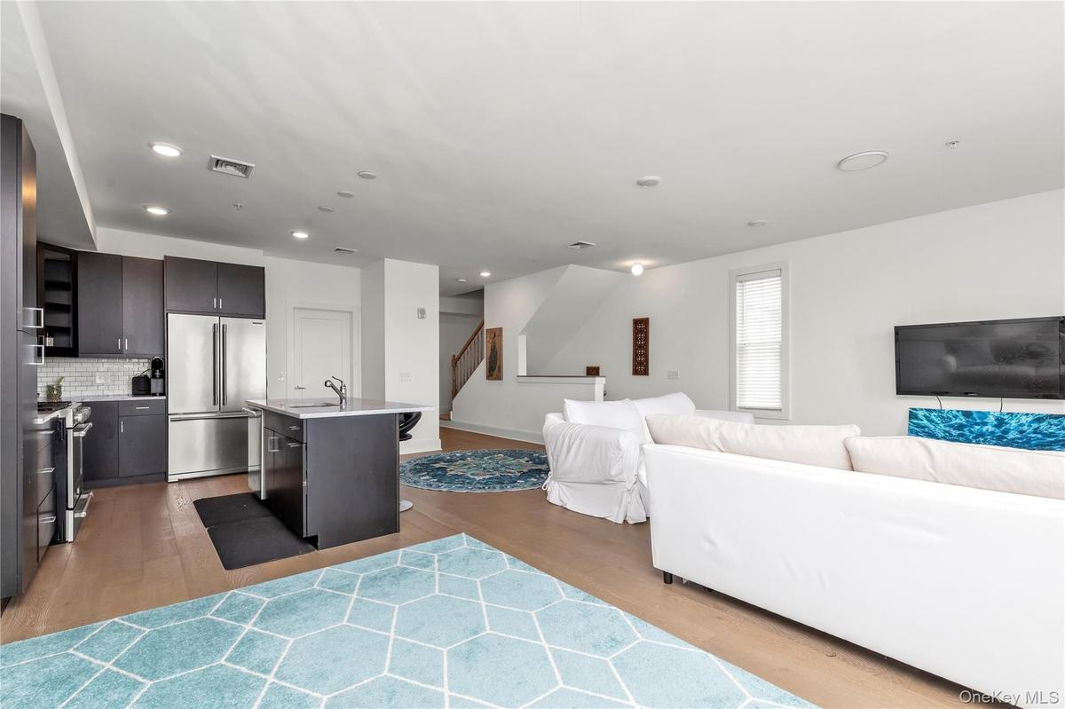 Living area with light wood-style flooring, stairway, and recessed lighting