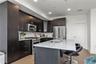 Kitchen featuring premium appliances, decorative backsplash, light stone countertops, a center island with sink, and a breakfast bar