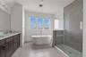 Full bathroom with double vanity, a shower stall, and a freestanding tub
