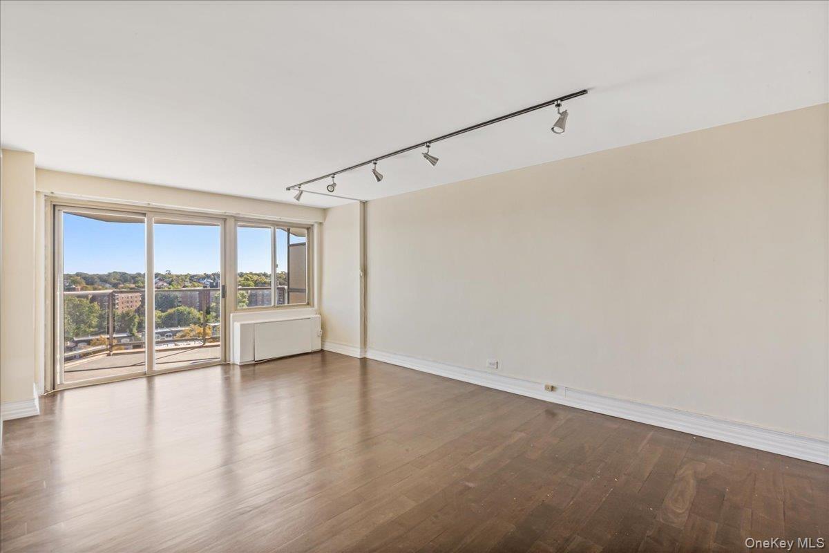Spare room with rail lighting and wood finished floors