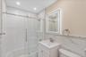 Bathroom with tile walls, bath / shower combo with glass door, and vanity