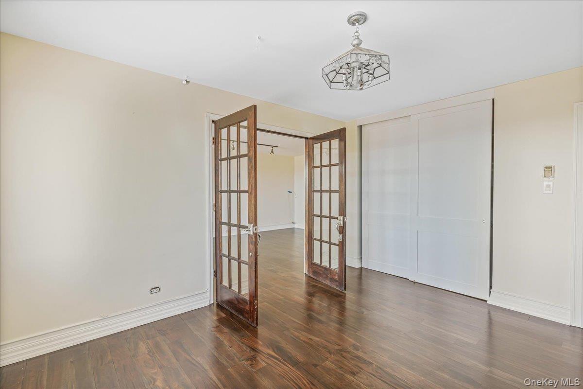 Unfurnished bedroom with french doors, dark wood-style floors, and a closet