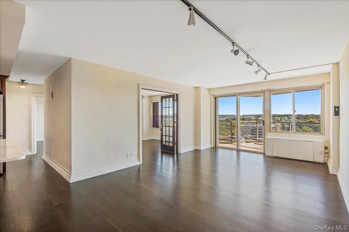 Unfurnished room featuring rail lighting and dark wood finished floors