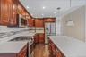 Kitchen featuring appliances with stainless steel finishes, dark wood-style flooring, tasteful backsplash, light stone counters, and recessed lighting