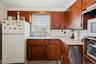 Kitchen with white appliances, under cabinet range hood, light countertops, decorative backsplash, and brown cabinets