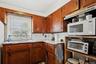 Kitchen featuring light countertops, white microwave, backsplash, brown cabinets, and freestanding refrigerator