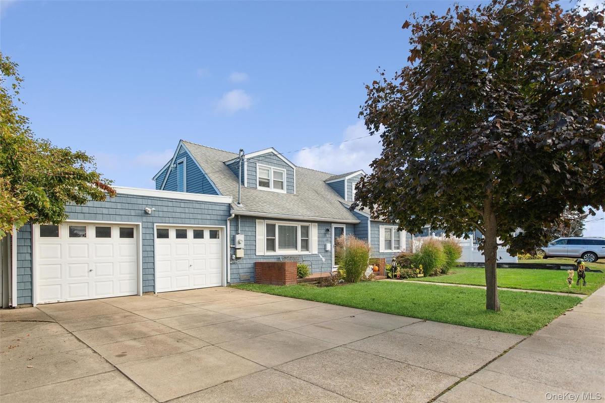 View of front facade with a front lawn, concrete driveway, a garage, and roof with shingles