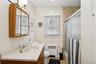 Bathroom with bath / shower combo with glass door, radiator heating unit, vanity, and light tile patterned floors