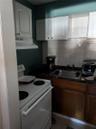 Kitchen with white electric range oven, light tile patterned floors, white cabinets, backsplash, and sink