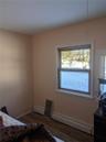 Bedroom featuring dark hardwood / wood-style flooring, a baseboard radiator, and multiple windows