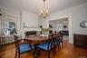 Dining room featuring a fireplace, a chandelier, wood-type flooring, ornamental molding, and radiator heating unit