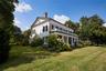 View of home's exterior featuring a chimney, a lawn, covered porch, and brick siding