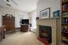Living room with radiator, light carpet, a fireplace with flush hearth, and ceiling fan