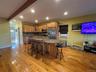 Kitchen with dark stone countertops, a center island, glass insert cabinets, a breakfast bar, and tasteful backsplash