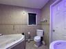 Bathroom with tile walls, light tile patterned flooring, a jetted tub, and a baseboard heating unit