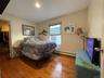 Bedroom with a spacious closet, wood finished floors, baseboard heating, and recessed lighting