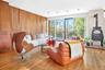Living room with a wood stove, light wood finished floors, and wood walls