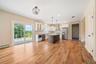 Kitchen featuring a center island, stainless steel appliances, wall chimney exhaust hood, pendant lighting, and white cabinetry