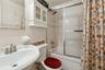 Full bathroom featuring shower / bathtub combination with curtain, sink, tile walls, and toilet