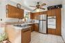 Kitchen featuring white appliances, sink, ceiling fan, and light tile floors