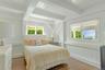 Bedroom with wood finished floors, multiple windows, beam ceiling, and a decorative wall