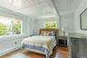 Bedroom featuring dark wood-style flooring, beamed ceiling, and wooden walls