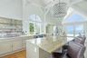 Kitchen featuring high vaulted ceiling, stainless steel fridge, a kitchen breakfast bar, plenty of natural light, and a water view