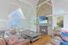 Living area with a fireplace, wood finished floors, high vaulted ceiling, beam ceiling, and plenty of natural light