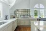 Kitchen featuring plenty of natural light, dark wood finished floors, vaulted ceiling, light stone counters, and white stovetop