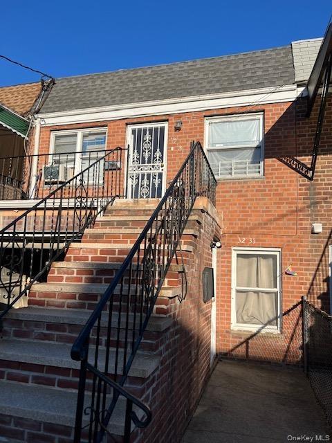 View of exterior entry featuring a shingled roof and brick siding