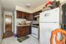 1st floor Kitchen with white appliances, light countertops, tasteful backsplash, dark brown cabinets, and under cabinet range hood