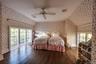 Bedroom with wood finished floors, wallpapered walls, and ceiling fan