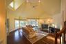 Living area featuring high vaulted ceiling, plenty of natural light, dark wood-style flooring, a tile fireplace, and a ceiling fan