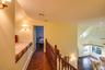 Corridor with vaulted ceiling, dark wood-style floors, and an upstairs landing