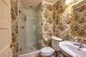 Bathroom featuring wallpapered walls, a stall shower, and tile patterned floors
