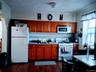 Kitchen with white appliances, dark wood finished floors, arched walkways, tasteful backsplash, and brown cabinets