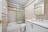 Bathroom featuring tile walls, vanity, toilet, and shower / bath combination with glass door