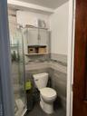Bathroom with tile walls, a stall shower, dark tile patterned flooring, and wainscoting
