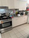 Kitchen with stainless steel range oven, light tile patterned floors, extractor fan, and decorative backsplash