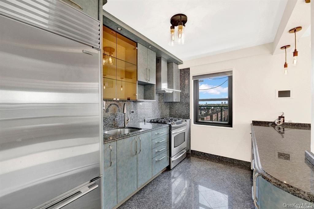 Kitchen featuring appliances with stainless steel finishes, granite floors, wall chimney exhaust hood, dark stone countertops, and tasteful backsplash