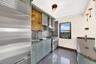Kitchen featuring appliances with stainless steel finishes, granite floors, wall chimney exhaust hood, dark stone countertops, and tasteful backsplash